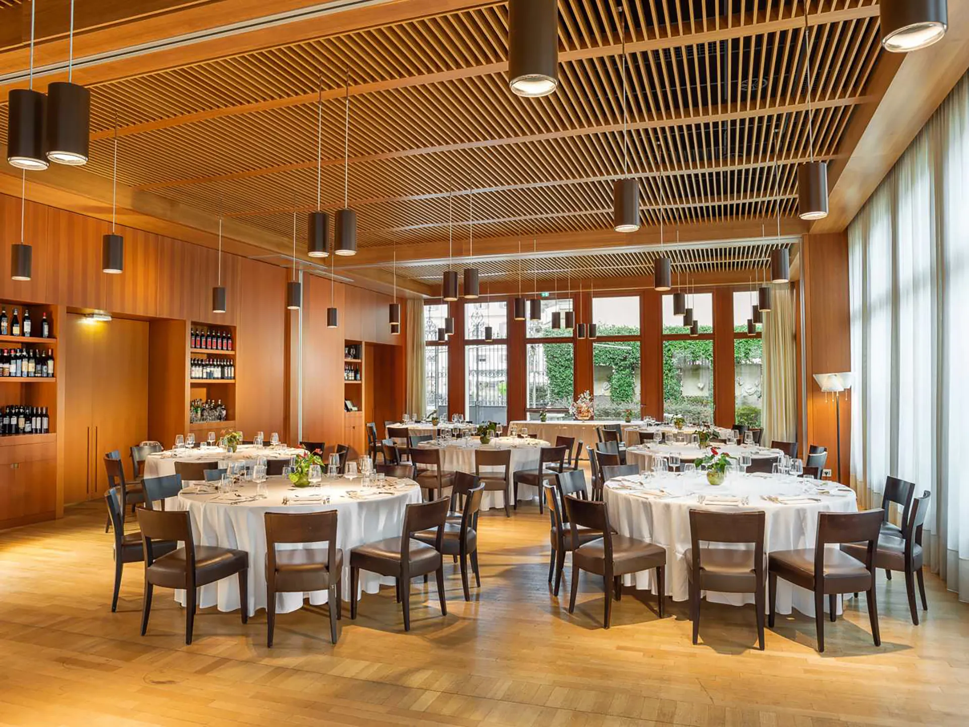 Nell'immagine, il Salone delle Feste presso il Grand Hotel della Posta con alcuni tavoli apparecchiati. Sulla sinistra, si intravedono dei ripiani su cui sono poggiate delle bottiglie di vino.