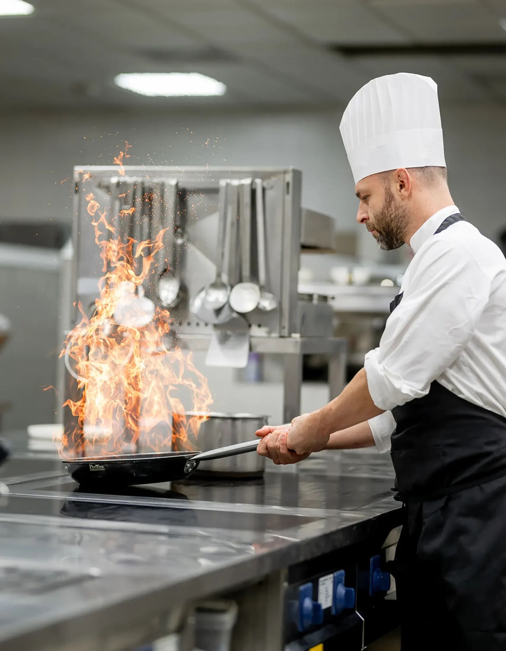 Nell'immagine, un dettaglio delle cucine del ristorante del Grand Hotel della Posta: si vede uno chef intento a flambare in padella una pietanza.